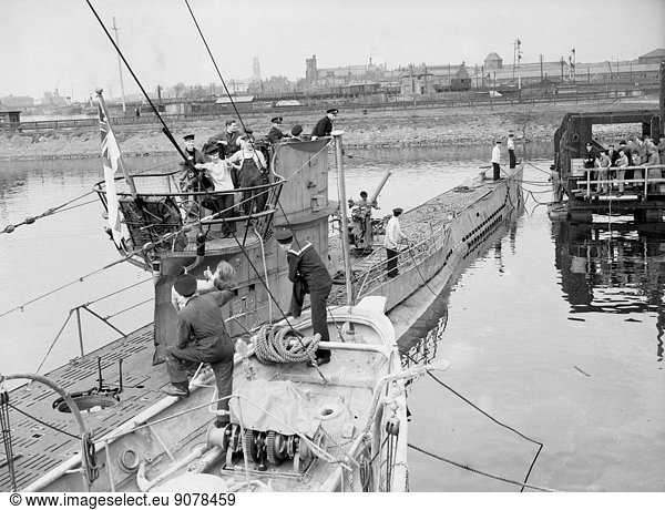 WW2  German U Boat Submarine. First German U Boat to be captured intact is sailed into port with a Royal Navy crew on board. The Submarine is met at the quayside with well done thumbs up gestures by other sailors.