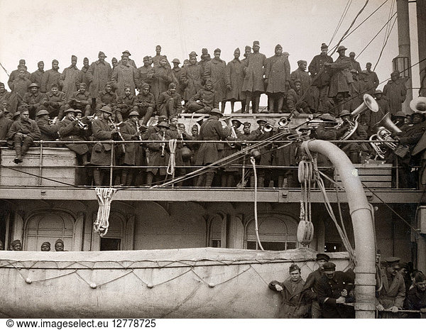 WWI: HOMECOMING  1919. Troops of the 369th Infantry Regiment (formerly the 15th Infantry New York National Guard) listening to the band play a final song before disembarking the 'SS France' in Hoboken  New Jersey. Photograph  1919.