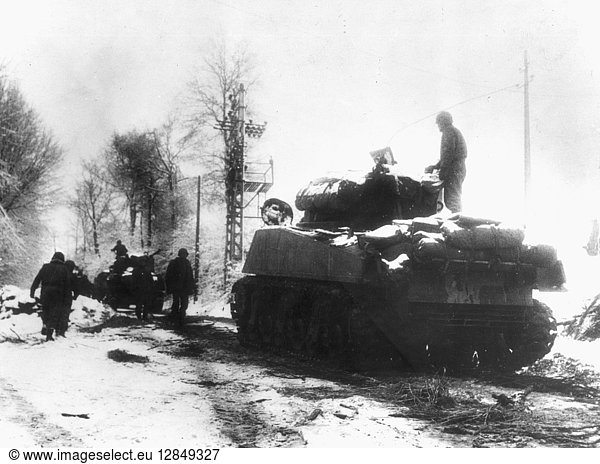 WWII: BATTLE OF THE BULGE. Tanks and infantrymen of the 82nd Airborne Division push through the snow in Belgium: December  1944.