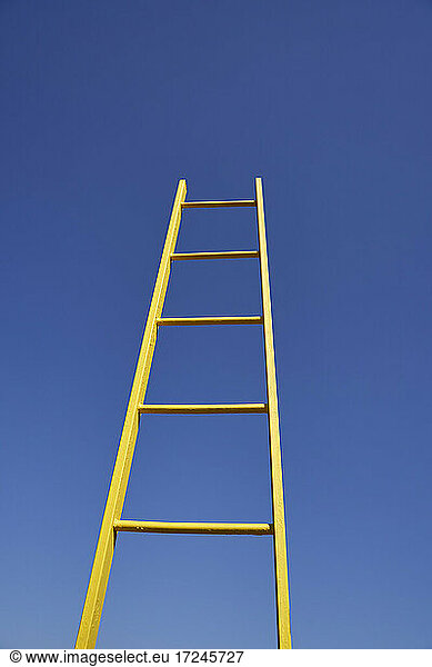 Yellow ladder by clear blue sky