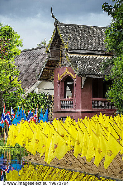 Yellow prayer flags in front of a wat temple  bright colours.
