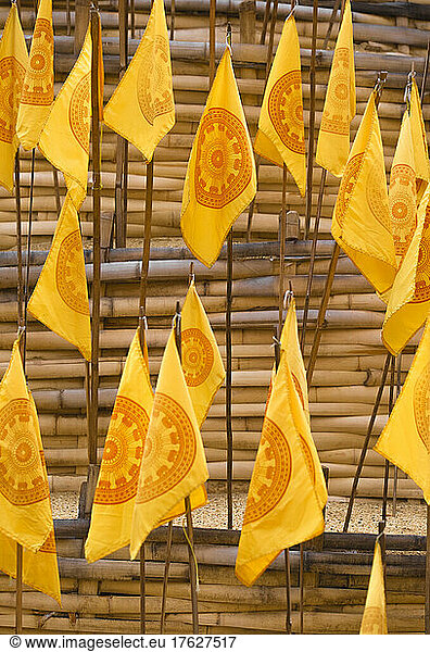 Yellow prayer flags stuck in sand at a wat temple.