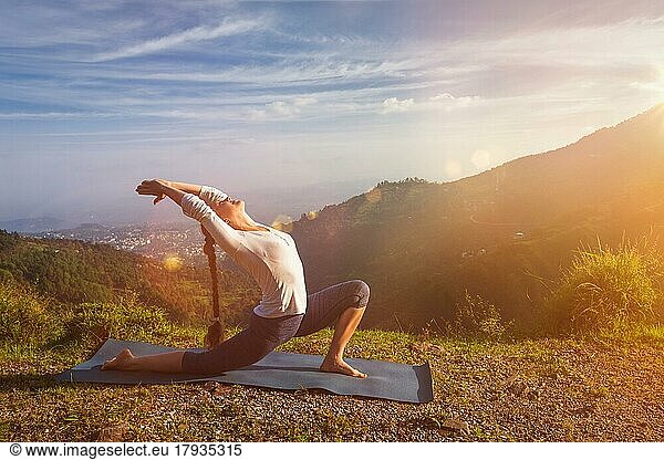 Yoga im Freien  sportlich fit Frau Praktiken Yoga Anjaneyasana  niedrige Halbmond Ausfallschritt Pose im Freien in den Bergen am Morgen. Mit Streulicht und Linsenreflexion