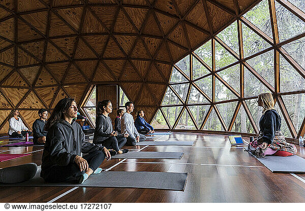 Yoga instructor and tourists practicing breathing exercise at health retreat