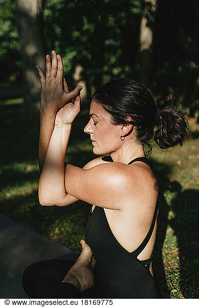 Yoga teacher with eyes closed exercising vajrasana garudasana posture in park