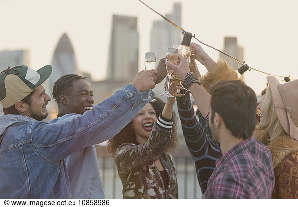 Young adult friends toasting champagne glasses at rooftop party