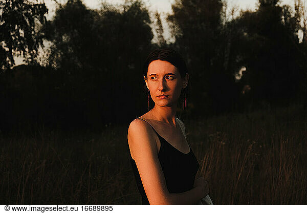 Young adult woman in dress posing at sunset. Low key portrait of