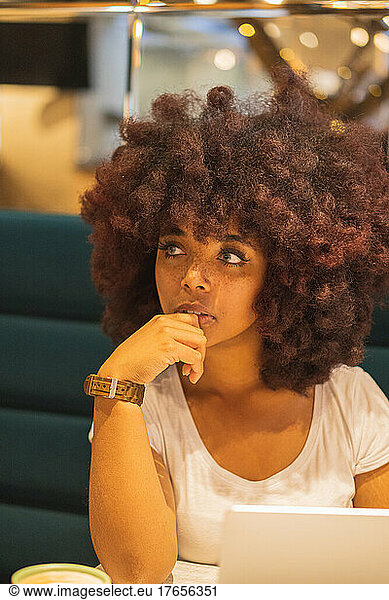 Young Afro woman in a coffee shop working online at her computer.