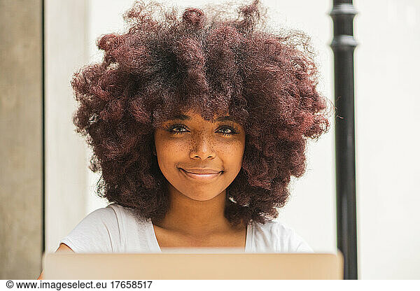 Young Afro woman in a coffee shop working online at her computer.