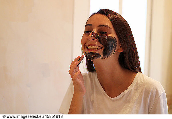 Young and attractive girl applying a brown sugar mask.