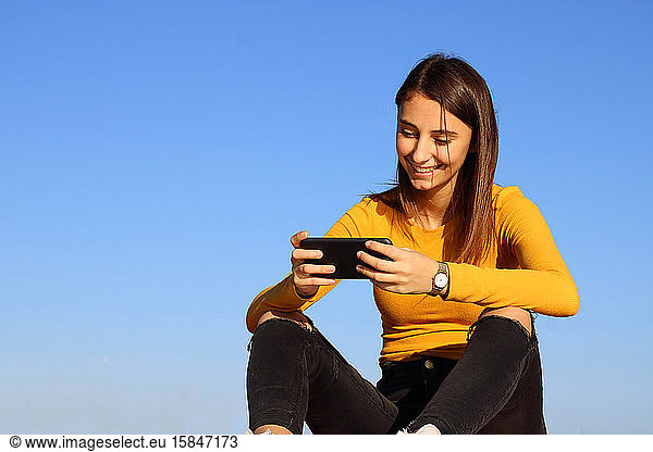Young and beautiful girl playing a game on her cell phone.