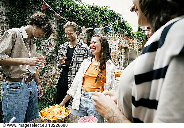 Young and happy multiracial friends enjoying during dinner party in back yard