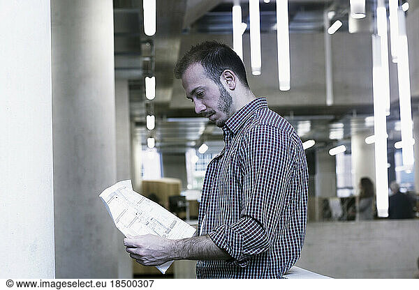 Young architect looking at blueprint in an office Freiburg im Breisgau  Baden-Württemberg  Germany
