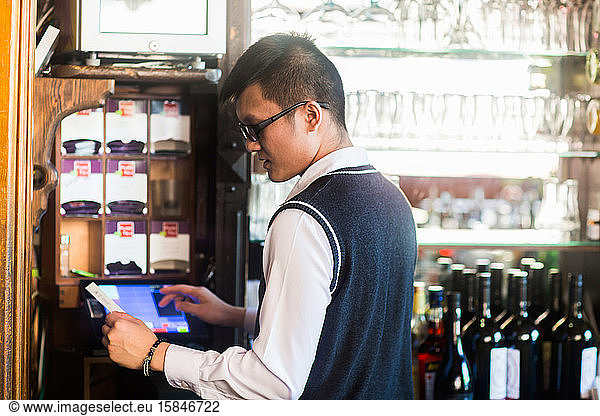 young asia waiter in a bar with a bill