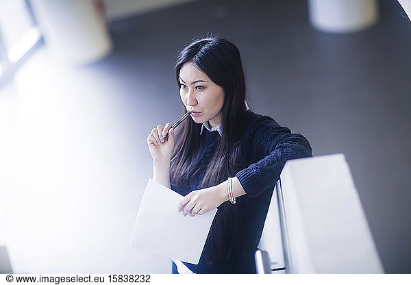 young asia woman with paper in an office standing with pen