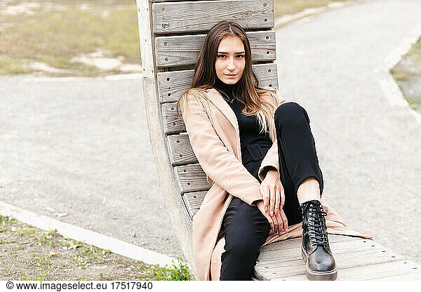 Young asian beautiful girl sitting on the wooden bench in park