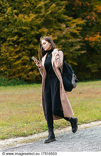 Young asian brunette girl walking with smartphone otdoor