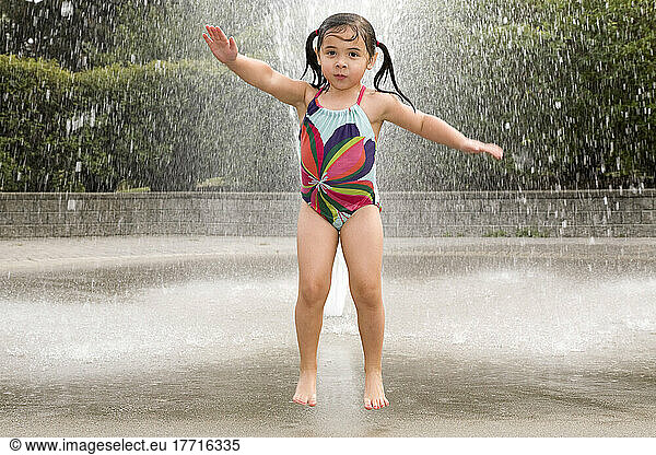 Young Asian-Caucasian Girl Jumping And Playing In A Water Sprinkler; Ontario Canada
