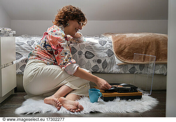 Young audiophile woman playing music on a turntable at her bedroom