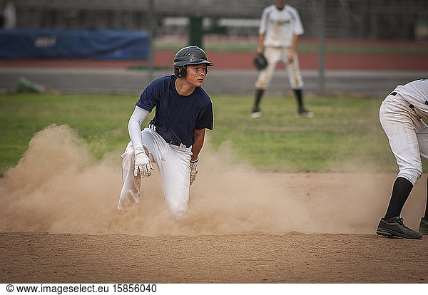 Young baseball player in cloud of dust after sliding into second base