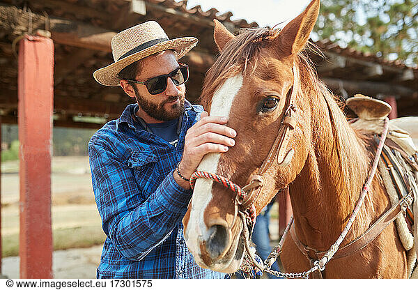 young bearded man having a lovely time with his horse in the field