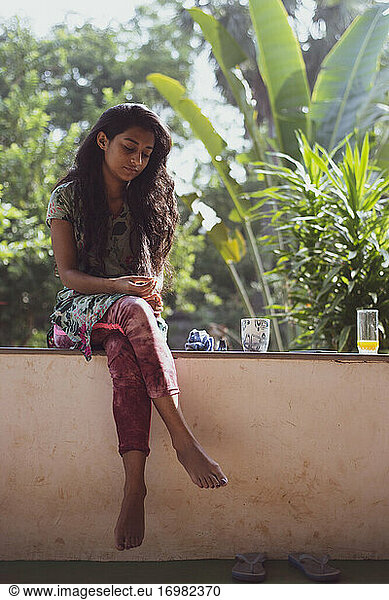 Young beautiful indian woman with tropical plants for morning coffee