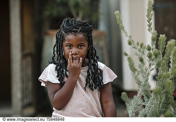 Young black girl with long braids and fingers in her mouth