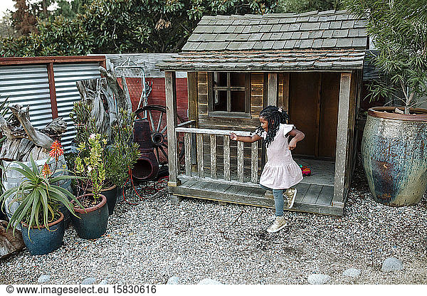 Young black girl with long braids jumping from wooden playhouse