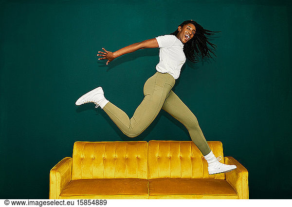 Young Black student jumping over a yellow coach.