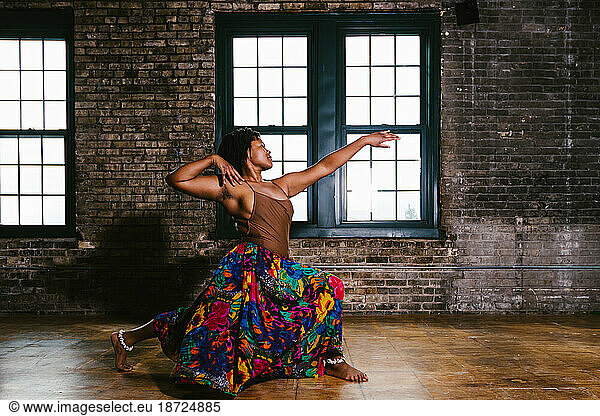 Young black woman does lunge move within dance by window