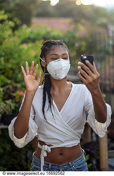 Young black woman in face mask doing a video call