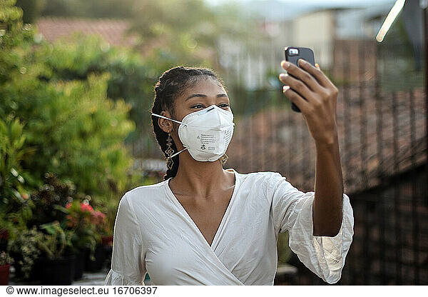 Young black woman in face mask using a smartphone