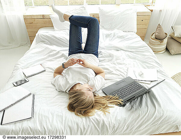 young blond female relaxing on the white bed