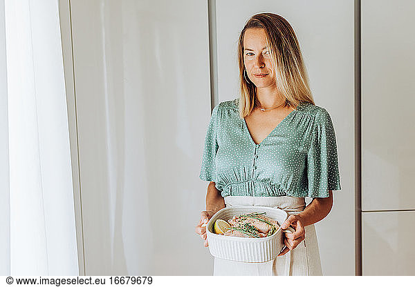 Young blond woman holding tray with food and looking at camera