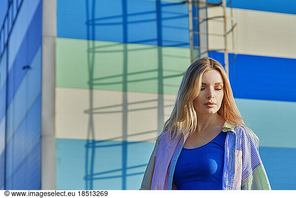 Young blond woman in the city against the stiped wall with shadows