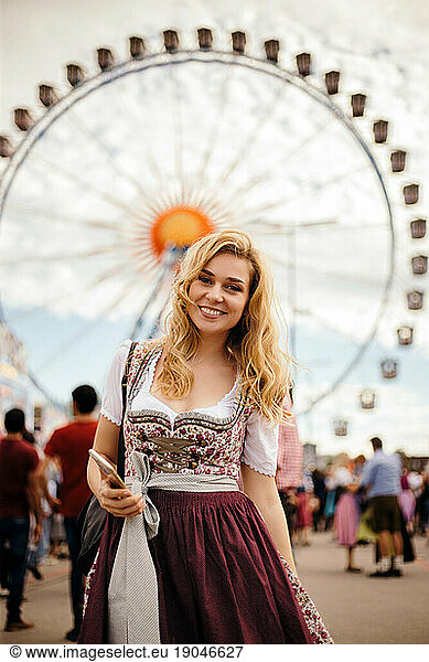 Young blond woman standing in front of Feriss wheel