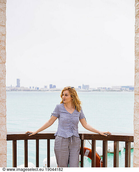 Young blond woman standing on terrace above the sea