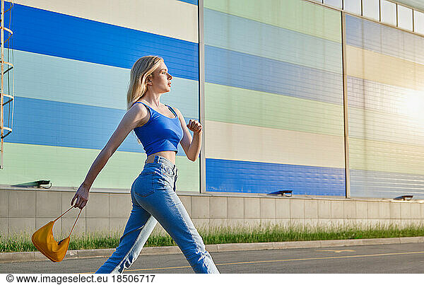 Young blond woman wearing blue jeans and top walking in the city