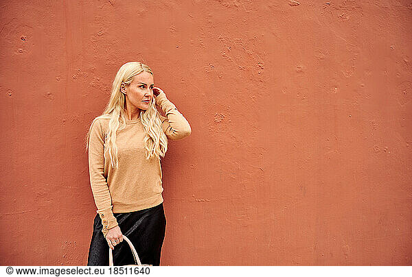 Young blonde female by colored wall