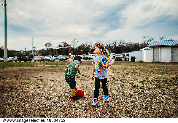 Young boy and girl playing soccer outside together