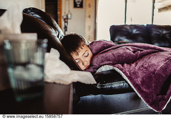 Young boy asleep on couch feeling ill