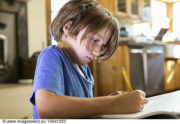 Young boy at home writing and drawing in his drawing pad