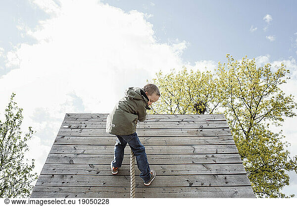 young boy climbing a climbing wall outdoors