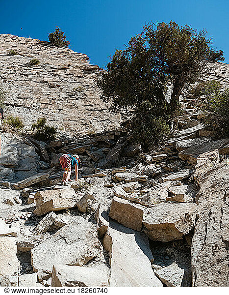 Young boy climbing rocky terrain on hike