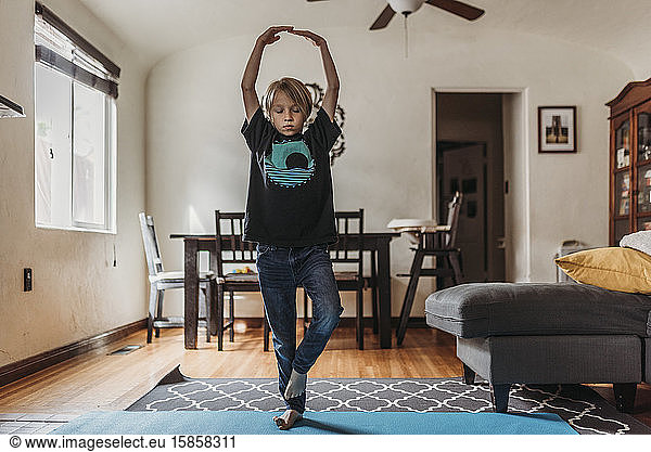 Young boy doing yoga in living room during isolation