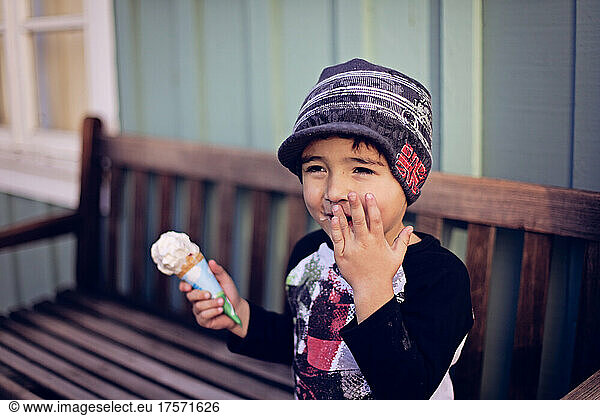 Young boy eating ice cream and laughing.