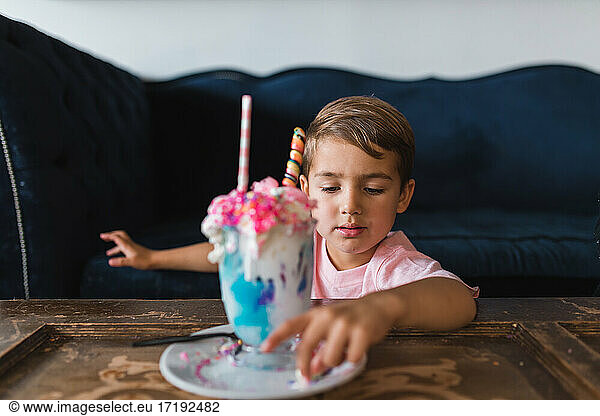 Young boy eating the candy off of a colorful milk shake.