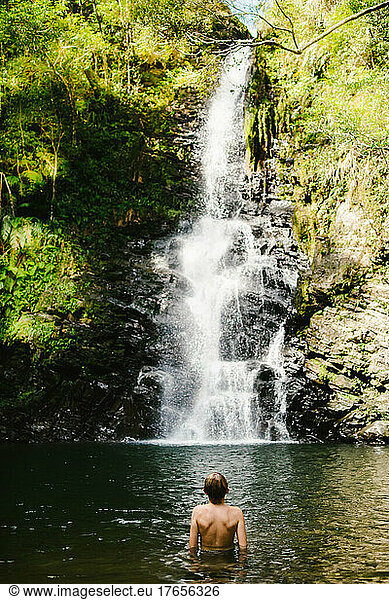 Young boy enjoys and love a large tropical waterfall