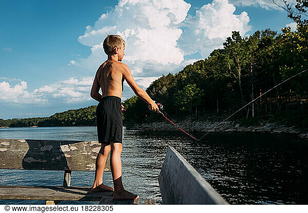 Young boy fishing off dock on sunny summer day