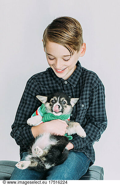Young boy holding puppy and smiling